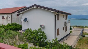 Um edifício branco com telhado vermelho, aparelhos de ar condicionado e vista para o mar.
