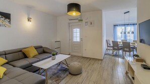 A modern living room with a sofa, coffee table, and a dining area with chairs and a table. - House Casa Maja (Brtonigla)