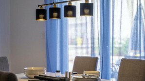 A dining table set with plates, cutlery, and a candle holder, with a modern pendant light fixture above. - House Casa Maja (Brtonigla)
