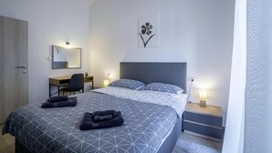A modern bedroom with a large bed, a desk, and a chair. There is a wall-mounted mirror and a bedside table with a lamp. - House Casa Maja (Brtonigla)