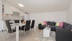 A modern kitchen with white cabinets and a dining area with a glass table and black chairs. - Apartments Family Spacious (Split)