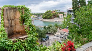 Une ville côtière dotée d’un port de plaisance, de bâtiments aux toits rouges et d’une végétation luxuriante.