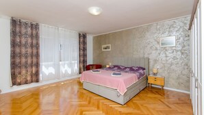 A bedroom with a bed, a nightstand, a window with curtains, and a picture on the wall. - Apartment Sun City (Split)