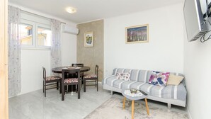 A compact living space with a dining area, a sofa, and a television. - Apartment Sun City (Split)
