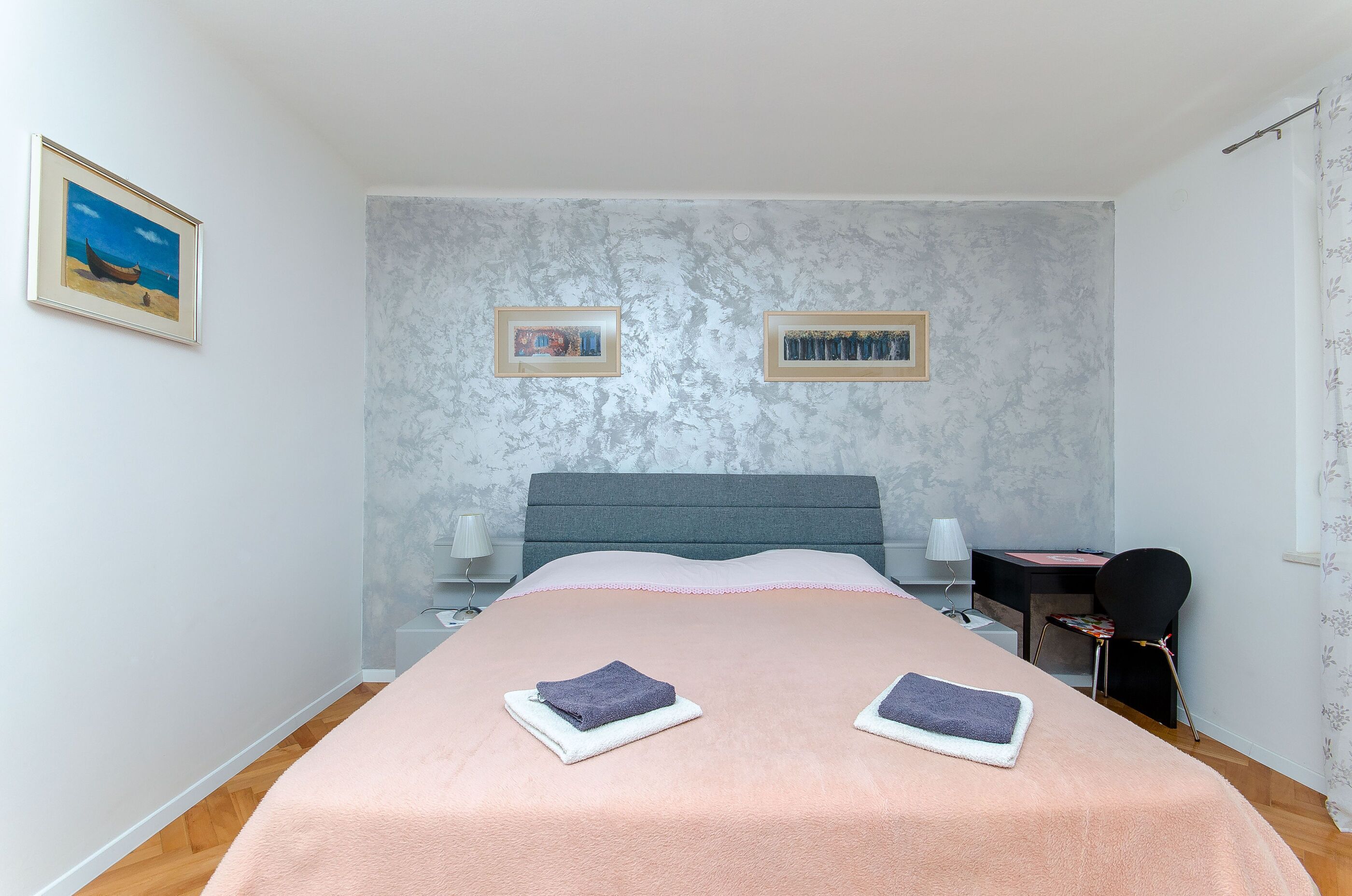Une chambre à coucher avec un lit, un bureau et deux tableaux encadrés accrochés au mur.