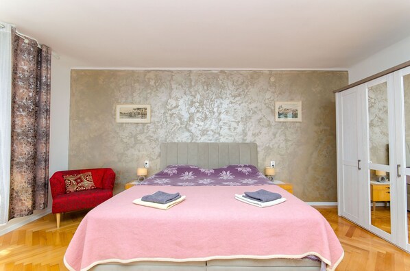 A bedroom with a bed, a red sofa, and a wardrobe. - Apartment Sun City (Split)