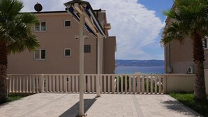 Un immeuble doté d’un balcon, de palmiers et offrant une vue sur la mer.