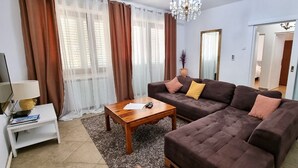 A living room with a brown sofa set, a wooden coffee table, a white side table with a lamp, and a large mirror. - Apartments Villa Privlaka Relax (Privlaka)