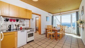 Una cucina con mobili in legno, una lavastoviglie e un fornello. C'è una zona pranzo con un tavolo e sedie.
