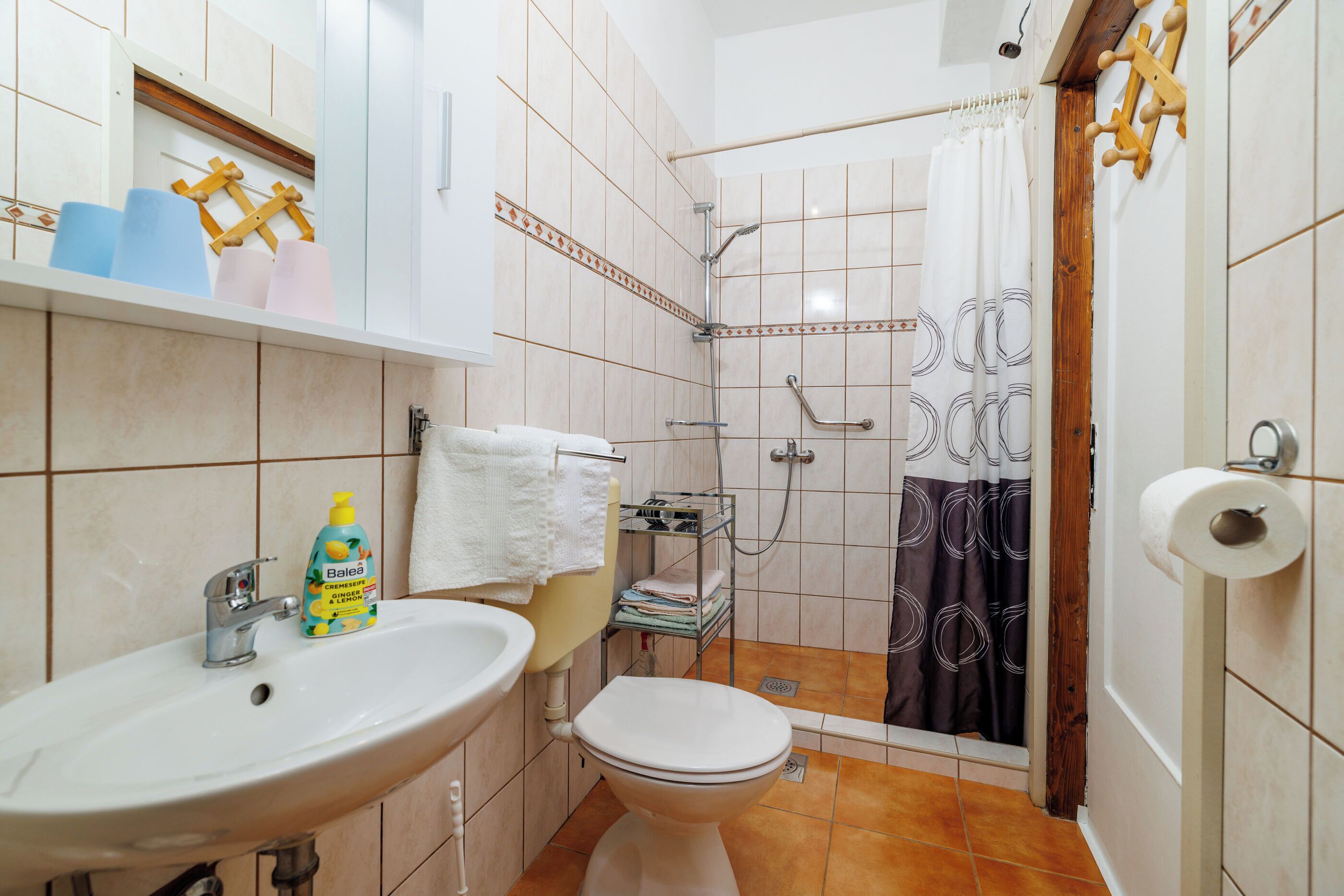 Un bagno con lavandino, water, doccia e porta asciugamani.