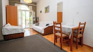 Una stanza con un letto, un divano, un tavolo da pranzo con sedie, un tappeto e un quadro appeso al muro.