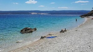A pebble beach with clear water and distant mountains. - House Nevenka (Omis)
