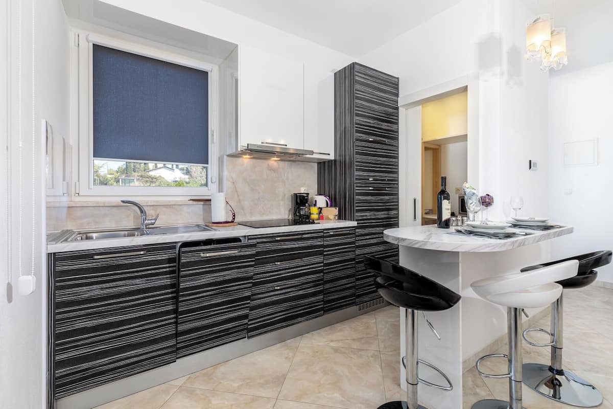 A modern kitchen with a built-in island, a window, and a bar area with stools.