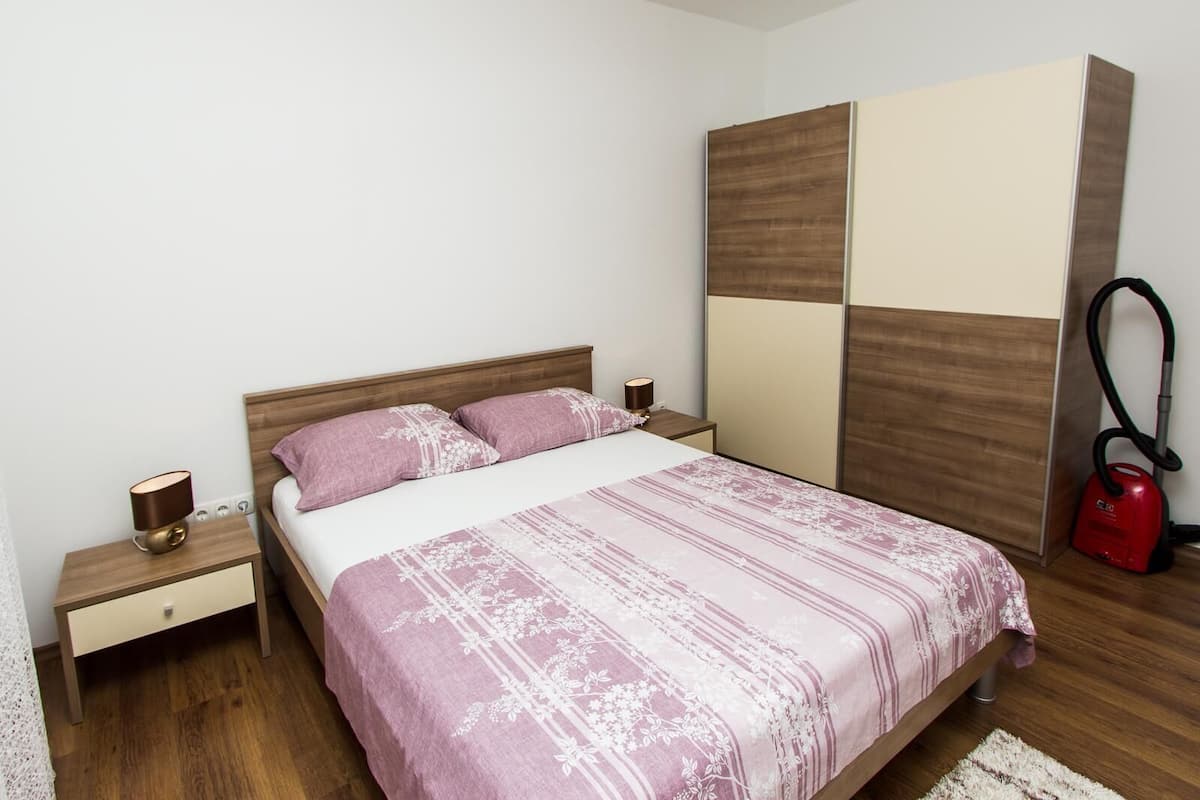 Ein Schlafzimmer mit einem Bett, Nachttischen, einem Staubsauger und Holzboden.