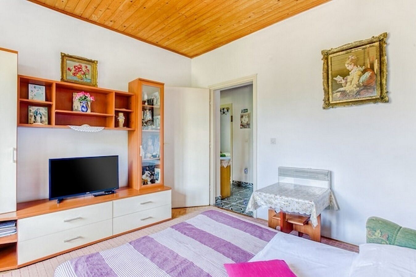 A bedroom with a TV, wooden furniture, a bed, and a small table.