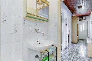 A bathroom with a white sink, a mirror, and a tiled floor. - Apartments Katin Kutak (Sibenik)