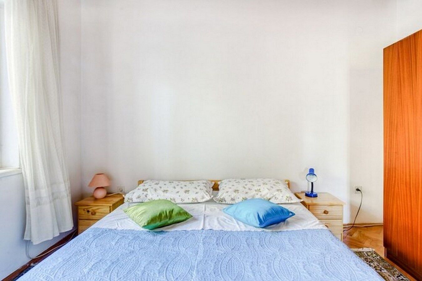 Un dormitorio con una cama, dos almohadas, una lámpara de noche y una mesita de noche.