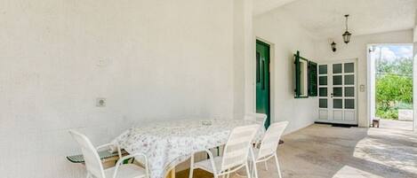 Comedor con una mesa, sillas, una puerta verde y vistas al exterior.