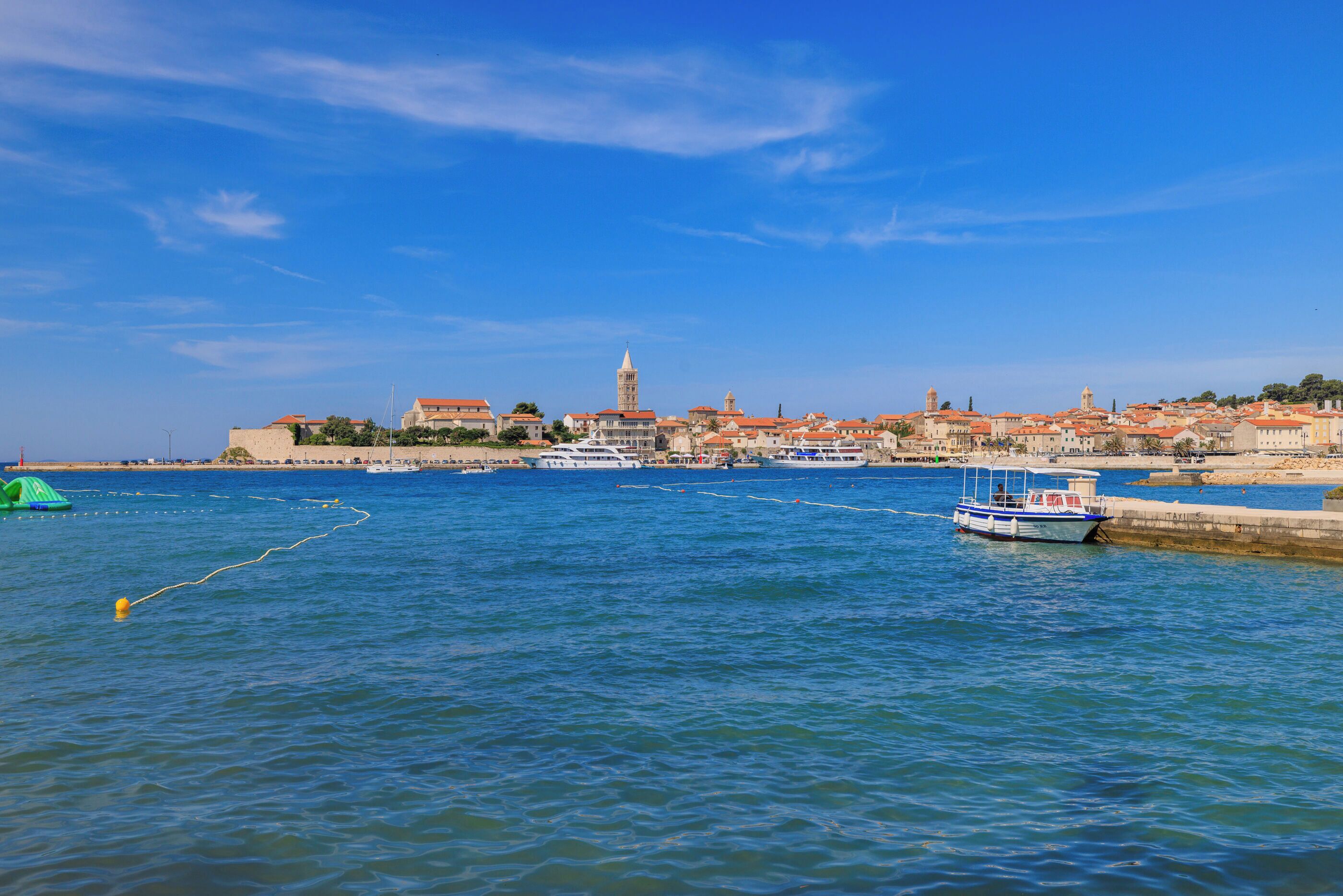 A coastal town with a prominent tower, calm waters, and boats.
