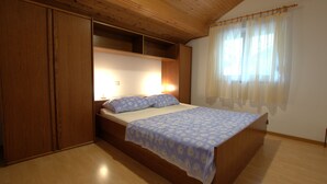 A bedroom with a wooden bed, a nightstand, and a wardrobe. - Apartment Ribaric (Rab)