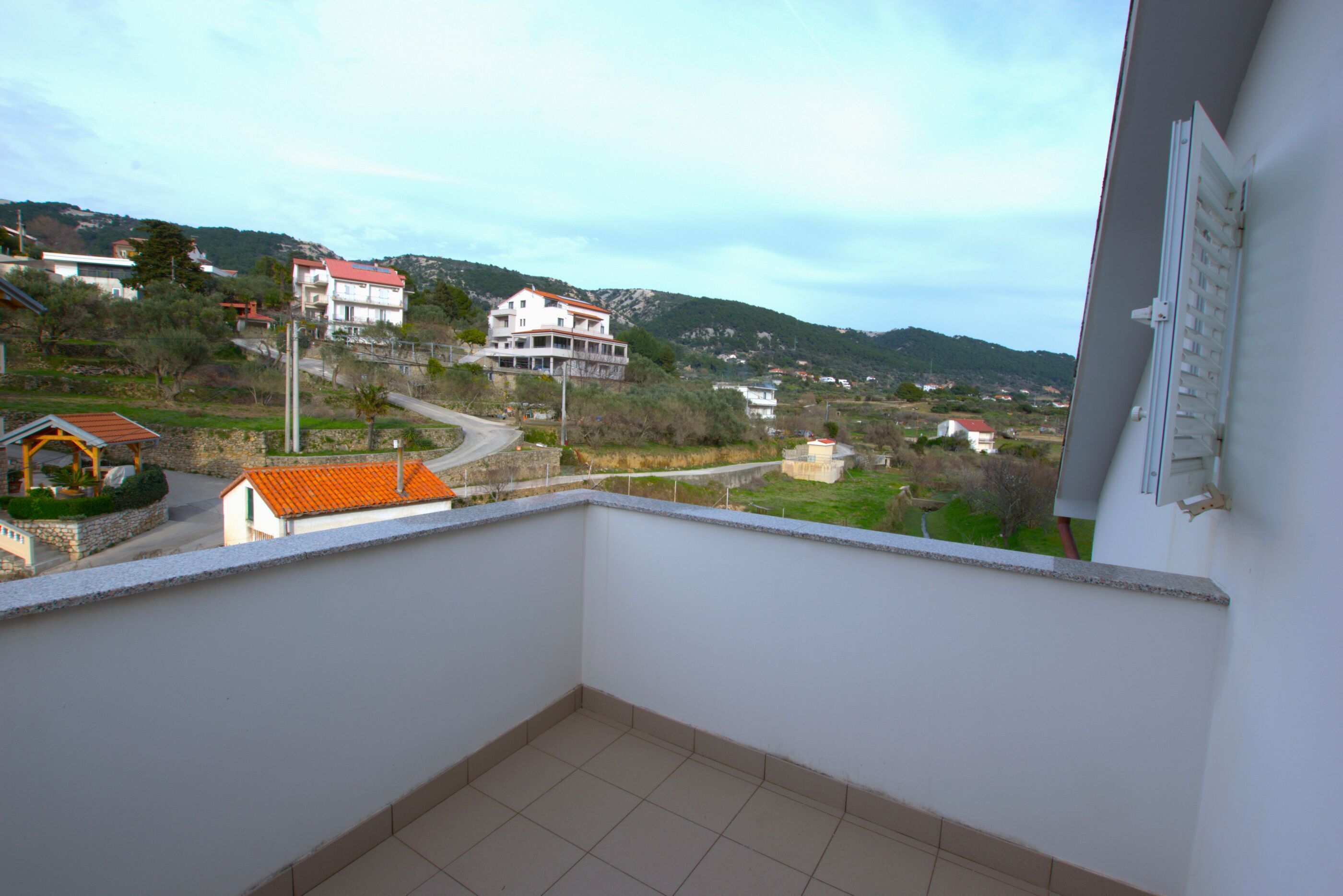 Un balcón con vistas a una zona residencial, con casas y una calle.