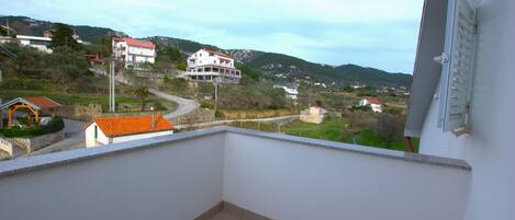 Un balcón con vistas a una zona residencial, con casas y una calle.