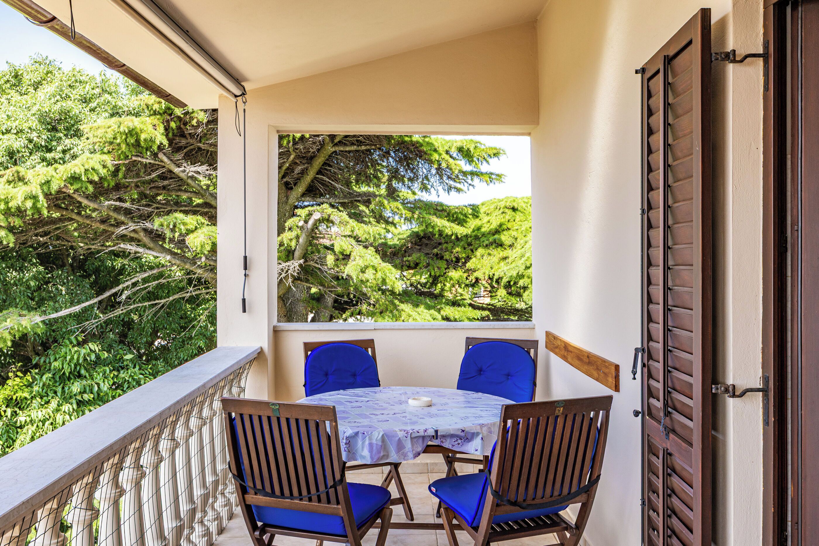 A balcony with a table and chairs, overlooking a lush green landscape.