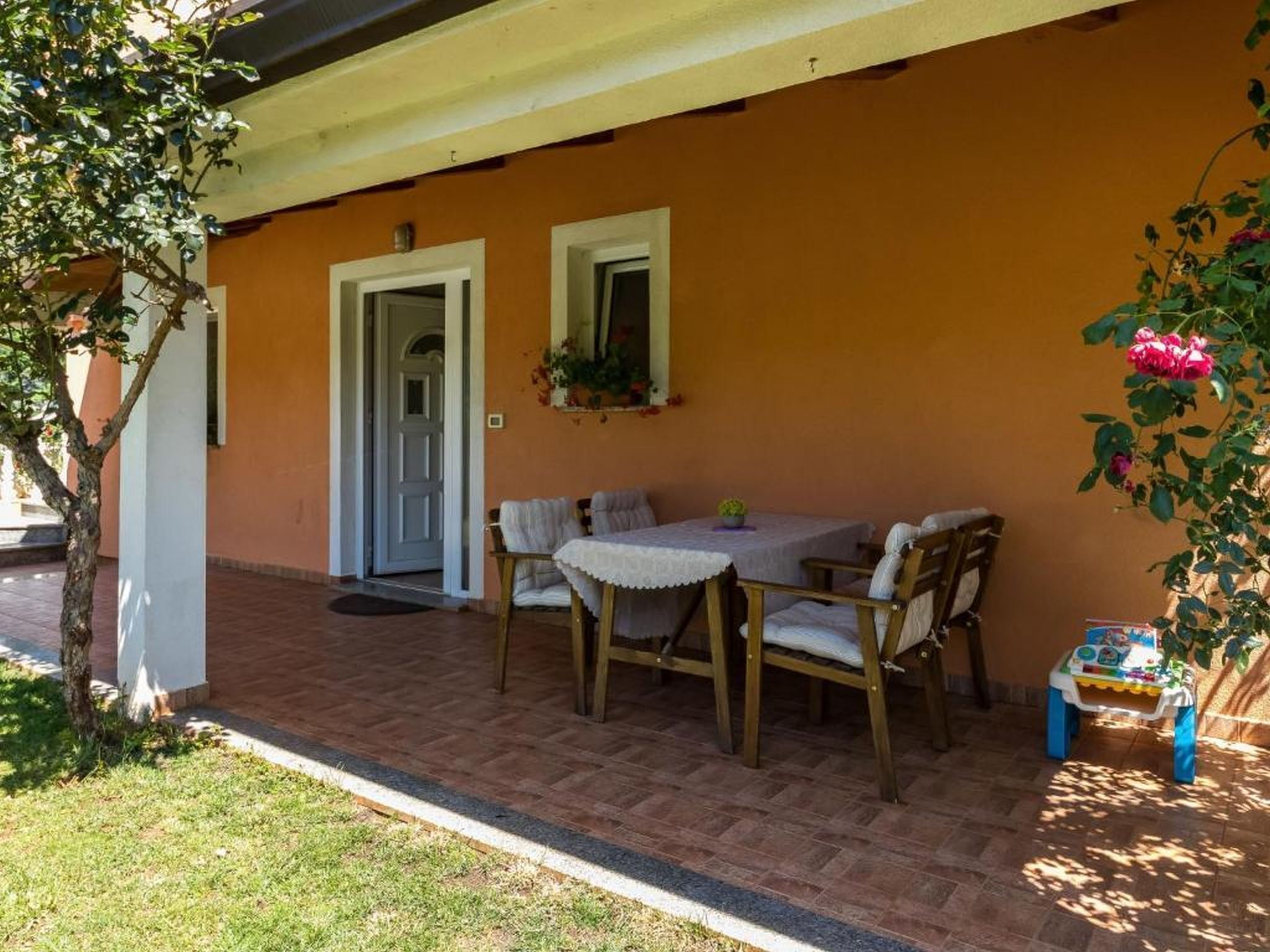 Un patio al aire libre con una mesa, sillas, una puerta y una mesita con juguetes infantiles.