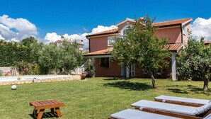 A villa with a swimming pool, a lawn, and lounge chairs. - House Haus Petar (Kastelir-Labinci)