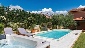 A swimming pool with lounge chairs and a hot tub in a backyard setting. - House Haus Petar (Kastelir-Labinci)