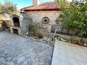 A stone building with a tiled roof, a stone oven, and a wheel. - Apartment Pogi Srima (Vodice)