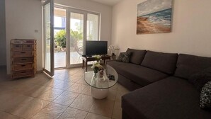A living room with a sofa, a coffee table, a TV, and a painting of a beach scene. - Apartment Pogi Srima (Vodice)