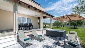 A covered outdoor area with lounge chairs, a hot tub, and a table. - Apartment Vista Olivo (Brtonigla)