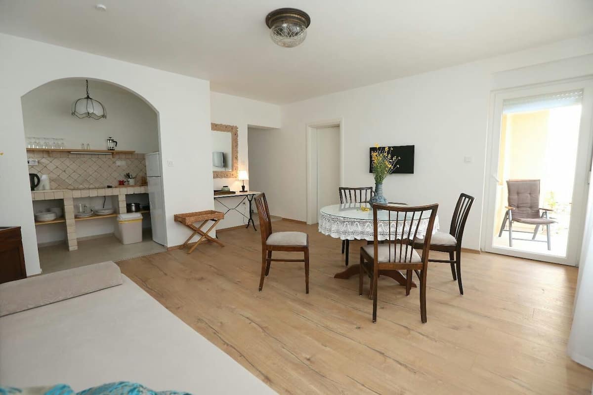A spacious living area with a dining table, chairs, and a kitchen in the background.