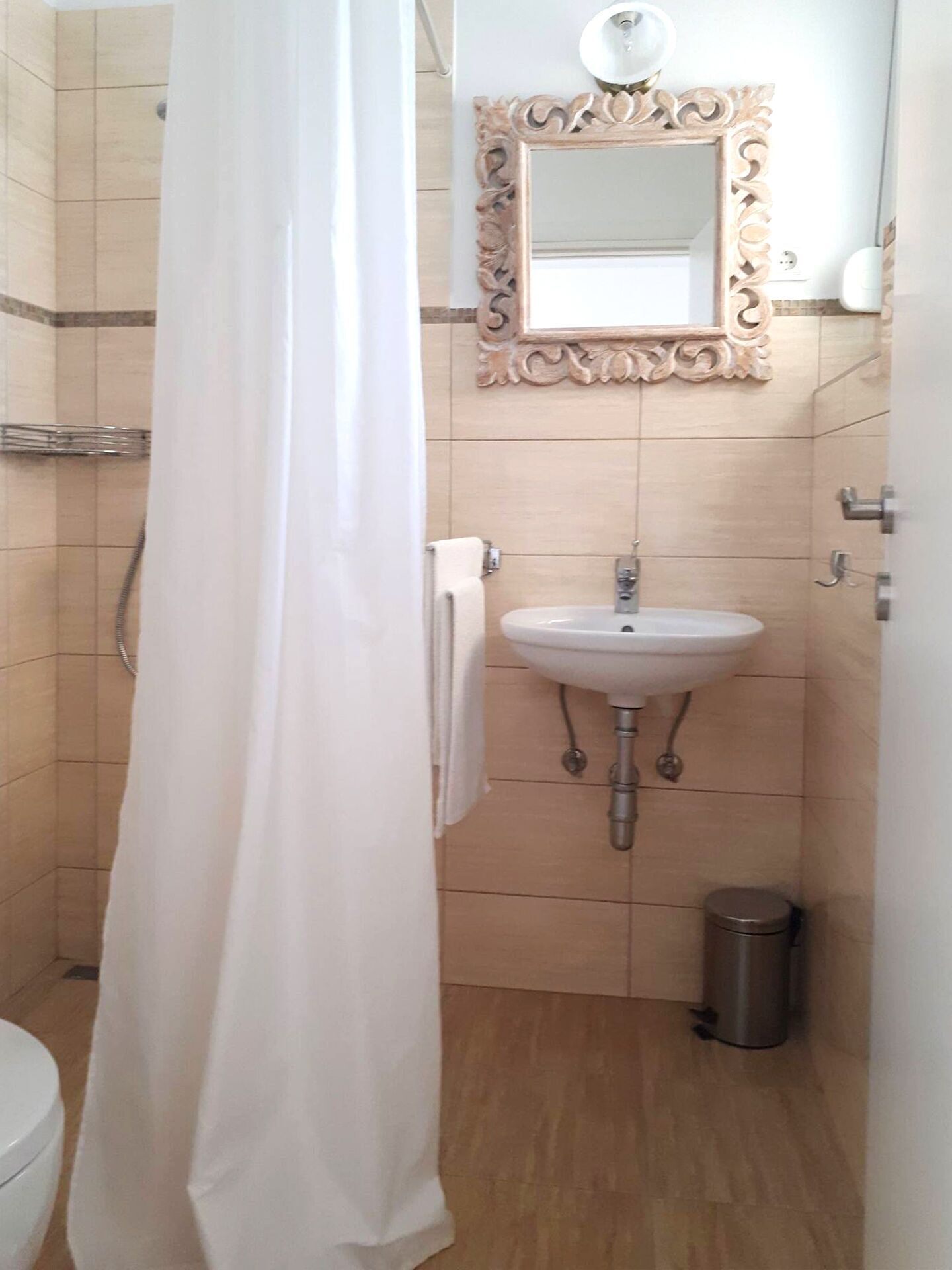 Une salle de bain avec un rideau de douche, un lavabo, un miroir et des toilettes.