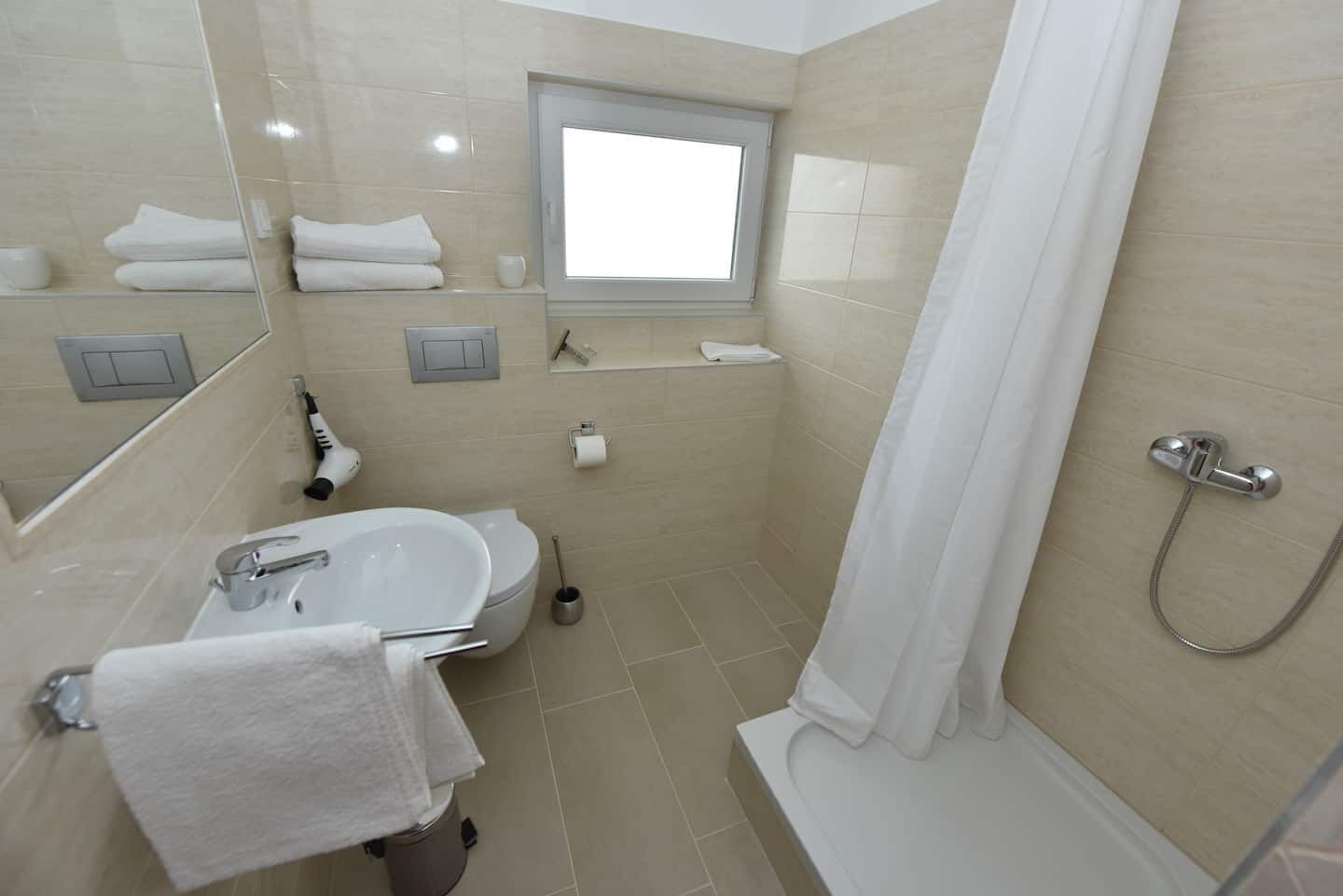 A modern bathroom with a sink, mirror, and shower.