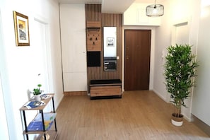 A hallway with a wooden floor, a small table with a plant, a wall-mounted cabinet, and a door. - Apartment Vesna (Split)