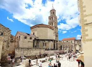 A historic square with a prominent tower, stone buildings, and a paved walkway. - Apartment Vesna (Split)