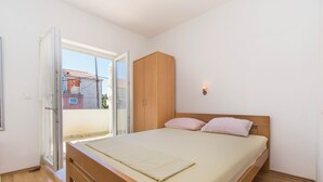 Ein Schlafzimmer mit einem Holzbett, einem Kleiderschrank und einer Glastür, die auf einen Balkon führt.