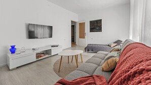 Ett modernt vardagsrum med en soffa, ett soffbord, en tv och en bokhylla.