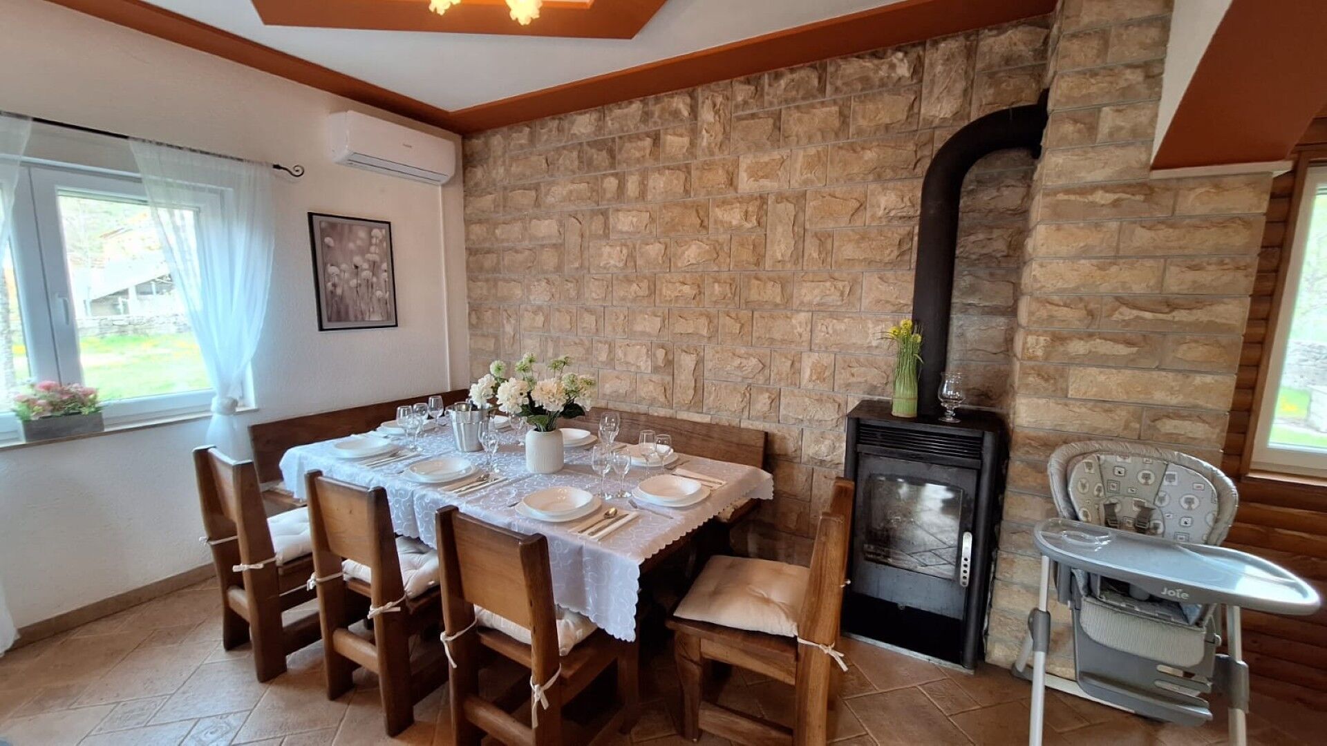 A dining area with a stone wall, a fireplace, and a table set for four.