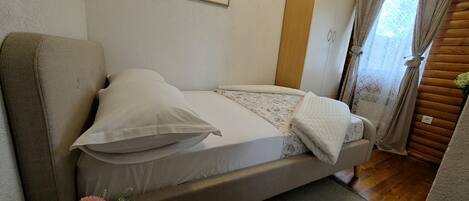 A single bed with a mattress, pillows, and a blanket.