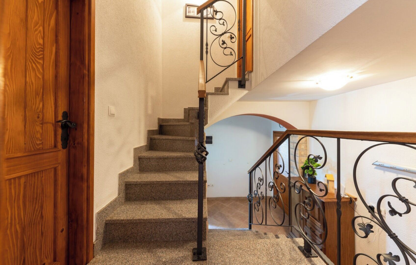 A staircase with a wooden door on the left and a metal railing on the right.