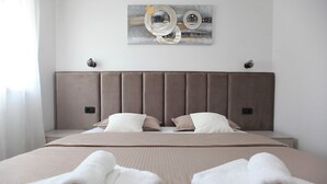 Una camera d'albergo moderna con un letto grande, due comodini e una testiera.