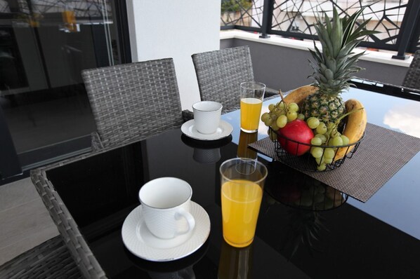 A dining table with chairs, a fruit basket, and two cups with a glass of orange juice. - Apartment Ivana (Trogir)