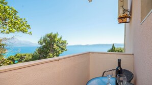 A balcony with a clear view of the sea and mountains, a bottle of wine, and two wine glasses. - Apartments Zvonko (Omis)