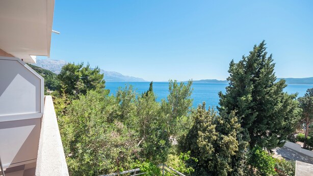 A balcony with a view of a clear blue sea and distant mountains. - Apartments Zvonko (Omis)