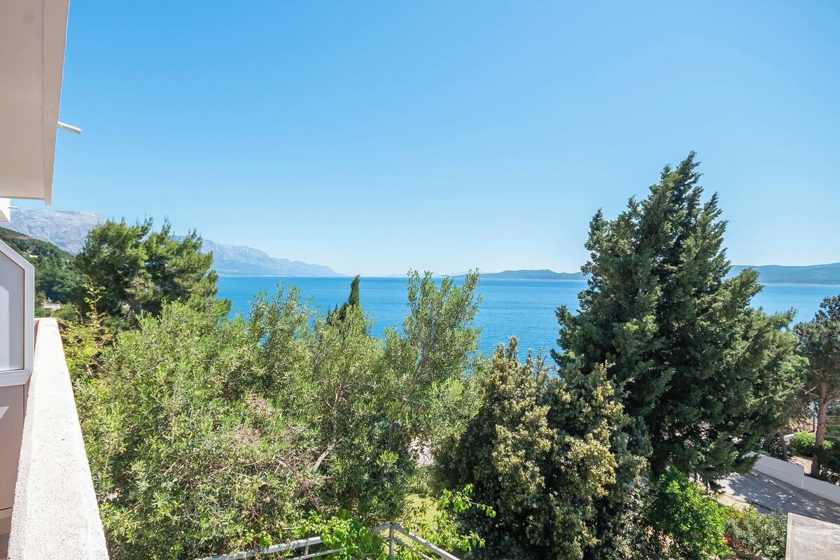 A balcony with a view of a clear blue sea and distant mountains.