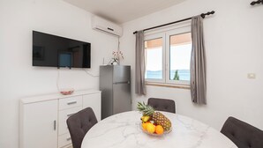 A dining area with a round marble table, a fruit bowl, and a television mounted on the wall. - Apartments Zvonko (Omis)