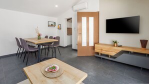 A modern dining area with a wooden table, chairs, a bench, and a flat-screen TV mounted on the wall. - House Prenc (Sveti Petar u Sumi)